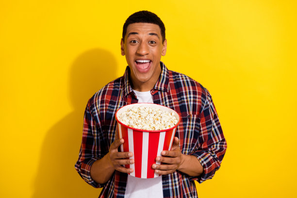 有吸引力的流行博主的照片漂亮的男人穿着时尚的格纹衣服，手拿红纸卡像孤立的黄色背景图片下载