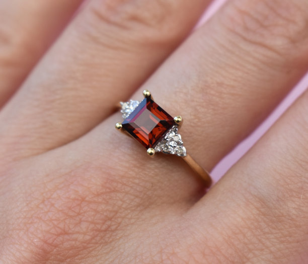 花式金戒指与红色宝石在一个女人的手，旧的复古珠宝概念，宣传照片为网上珠宝店图片下载