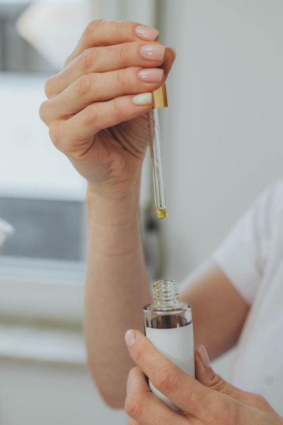 一个女人的手精致地拿着一个带滴管的瓶子，展示了优雅和精确图片下载