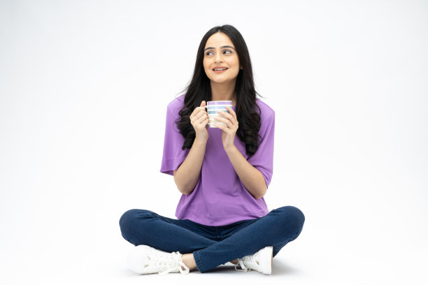 开朗可爱的女人穿着时髦的衣服坐在地板上喝咖啡，空白的空间孤立在白色背景的照片图片下载