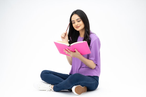 开朗可爱的女人穿着时髦的衣服，坐在地板上看书，空白的空间孤立在白色背景的照片图片下载