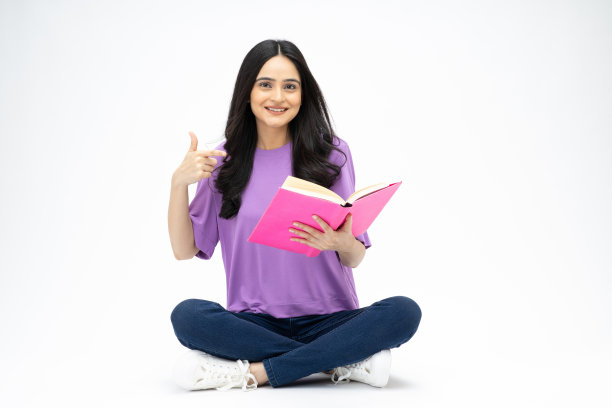 开朗可爱的女人穿着时髦的衣服，坐在地板上看书，空白的空间孤立在白色背景的照片图片下载