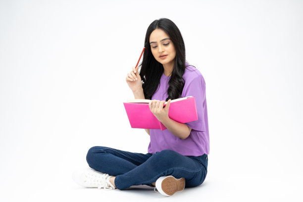 开朗可爱的女人穿着时髦的衣服，坐在地板上看书，空白的空间孤立在白色背景的照片图片下载
