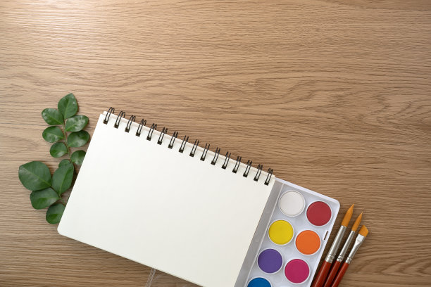 书和水彩颜料集和油漆刷木制纹理背景。办公桌空间图片下载