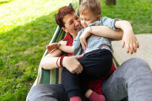 春天的一天，孙子和奶奶躺在院子里的躺椅上。祖母是有血有肉的种族，x一代。男孩皮肤和头发都很白。他们通过玩耍、拥抱和微笑享受在一起的时光。焊接时间。复制空间，库存照片图片下载