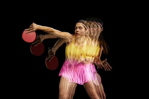 身着彩色运动服的年轻女子集中训练，在带有频闪效果的黑色背景下打乒乓球图片下载