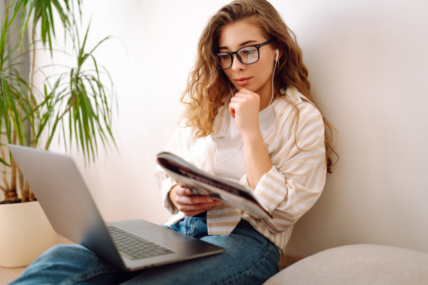 年轻的IT女性用笔记本电脑工作，呆在家里，酒店。图片下载