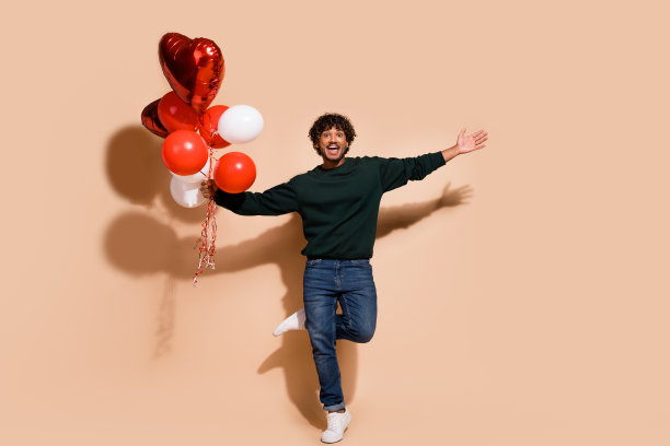 全长照片无忧无虑的积极的家伙穿着运动衫拿着气球空空间孤立米色背景图片下载