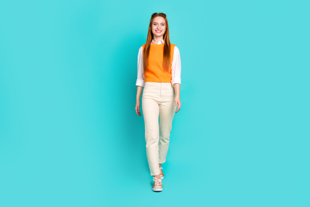 微笑的可爱的漂亮女孩的全身照片穿着时尚的服装去商场中心孤立的海蓝宝石色背景图片下载