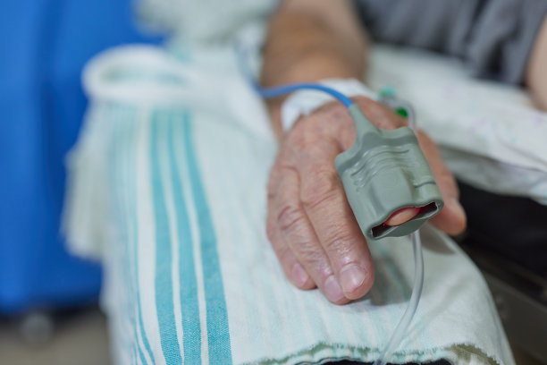 在医院的病床上，老人的手在输液的特写照片图片下载