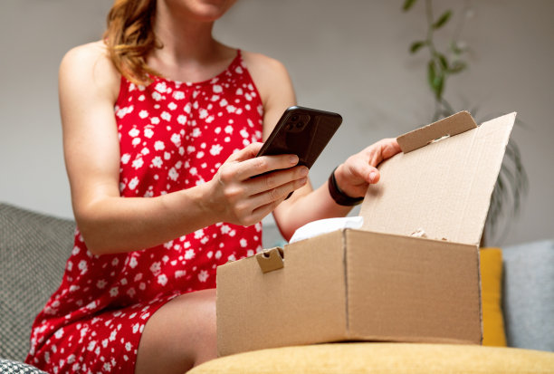 在家购物，拆包裹。一名女子打开她的在线订单，并在网上发布了她购买的照片。图片下载
