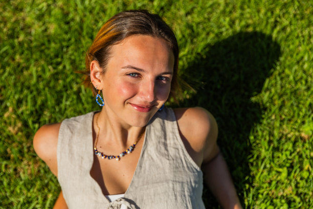 一个女人躺在草地上，在夏天微笑，照片从上面的复制空间图片下载