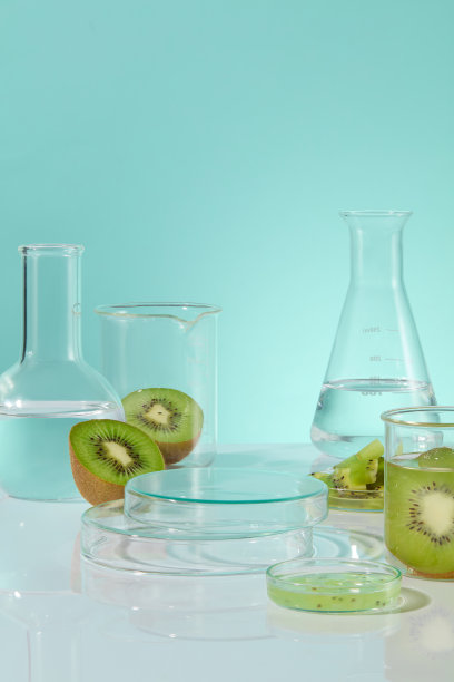 广告照片，中间放置空白玻璃底座，用于展示产品，周围是带有透明液体和新鲜猕猴桃的实验室玻璃器皿。照片是从正面拍摄的图片下载