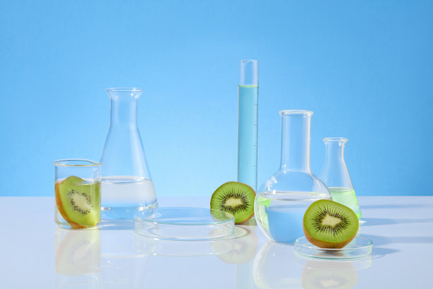 白色的桌子上摆放着大量的实验仪器，淡蓝色的背景，中间是空白的托盘，新鲜的绿色猕猴桃装饰。正面拍摄的广告照片图片下载
