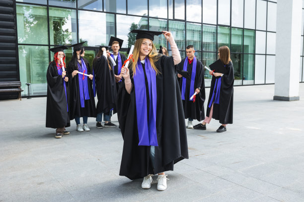 研究生站在长袍和文凭。图片下载