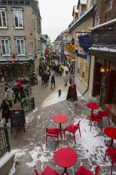 一个冬天的下午，游客们走在鹅卵石铺成的狭窄街道上，在魁北克老城历史悠久的店面里购物。图片下载