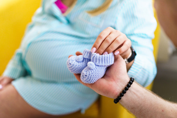 女人手上的小童鞋。穿着靴子的怀孕小姐。图片下载