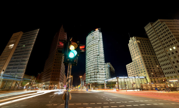 波茨坦广场一个繁忙的十字路口的夜间照片，有车辆痕迹和红绿灯。熙熙攘攘的城市景观在一个不安宁的十字路口与照明摩天大楼。现代德国概念-柏林，德国图片下载