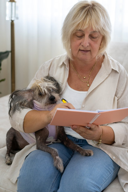 坐在客厅沙发上在计划本上书写的美丽年长女人图片下载