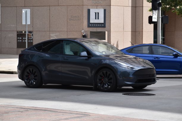 一辆灰色的特斯拉Y型电动汽车在市中心行驶图片下载