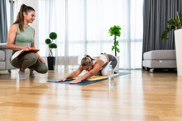与私人教练在家锻炼。两名年轻女性理疗师和客户进行稳定、身心健康的培训。女商人花钱请专业教练帮助她。图片下载