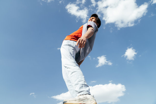 快乐的人在蓝天的背景。在蓝天的背景下，一个快乐微笑的亚洲男人的肖像照片。图片下载