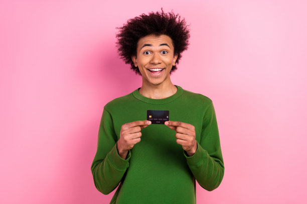 照片的快乐积极的家伙持有信用卡购买商品孤立柔和的颜色背景图片下载