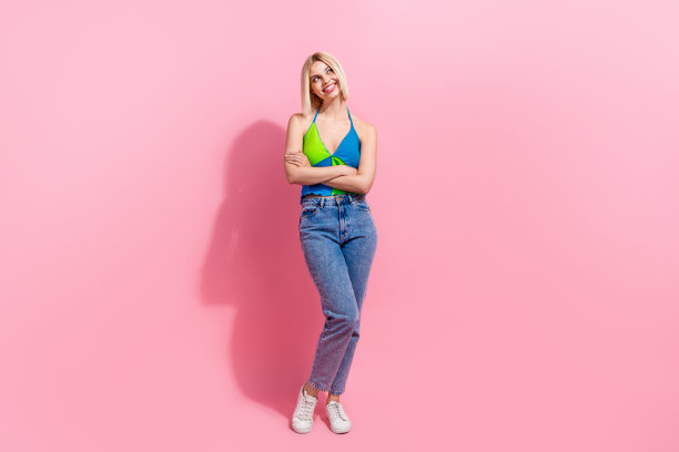 可爱的女人穿彩色牛仔裤的全尺寸照片梦幻般的看着销售空的空间双臂折叠孤立在粉红色的背景图片下载