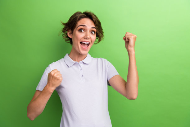 女运动员女孩穿着polo t恤举起拳头，拳击教练庆祝她的团队胜利，孤立的绿色背景图片下载