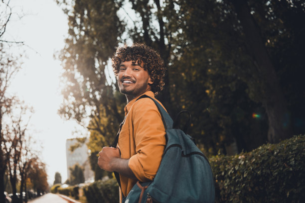 照片开朗的好心情的男人穿着时髦的衣服拿着背包走城市街道远足旅行旅行度假春天的天气外面图片下载