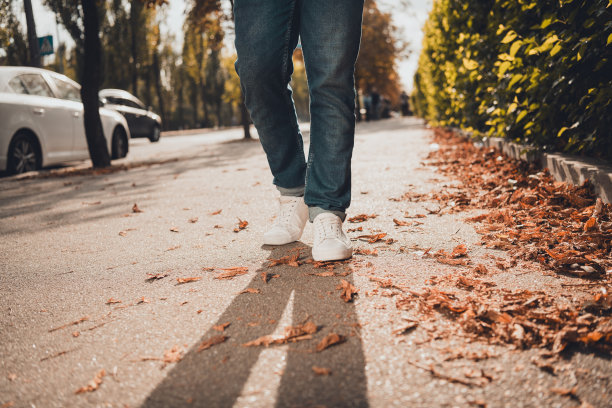 裁剪的照片，男子在时尚的运动鞋走在道路人行道的城市街道风格图片下载