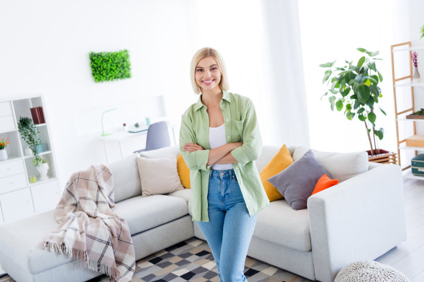 照片肖像迷人的年轻女子双手交叉房地产经纪人穿着时髦的绿色服装居住区域明亮的室内设计图片下载