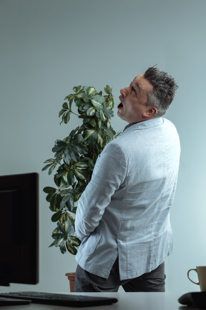 办公室男职员似乎在盆栽上撒尿图片下载