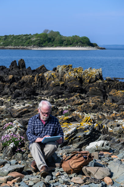 老人坐在石头上玩iPad图片下载