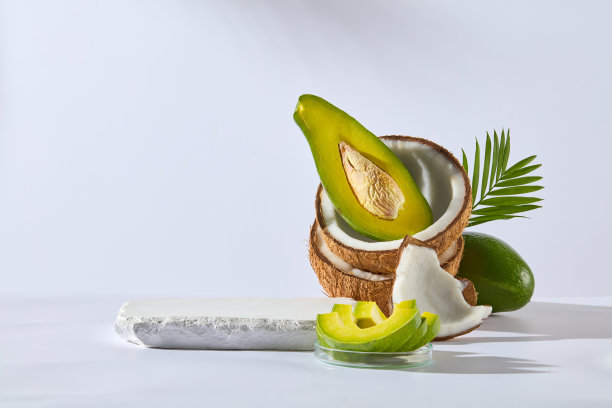 白色背景上的椰子和牛油果设计模板，一个空白的石膏讲台，展示产品的天然成分。照片正面拍摄，留白宣传图片下载