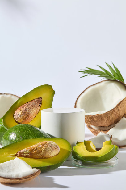 牛油果和椰子的照片在白色纹理，空白的圆形圆柱形底座与有机水果装饰，包括牛油果和椰子。显示空间，前视图图片下载