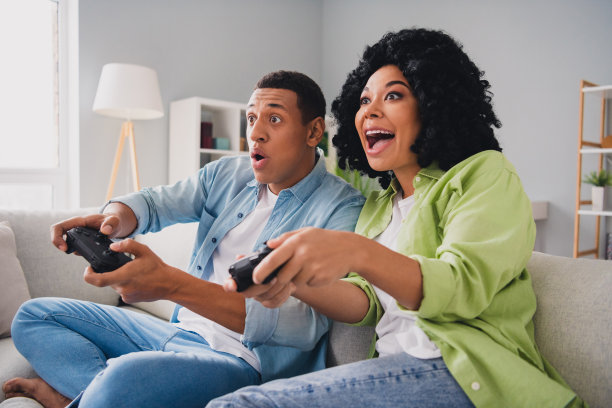 漂亮的年轻男子女孩的照片坐在沙发上玩电子游戏playstation现代室内室内舒适的日光公寓客厅图片下载