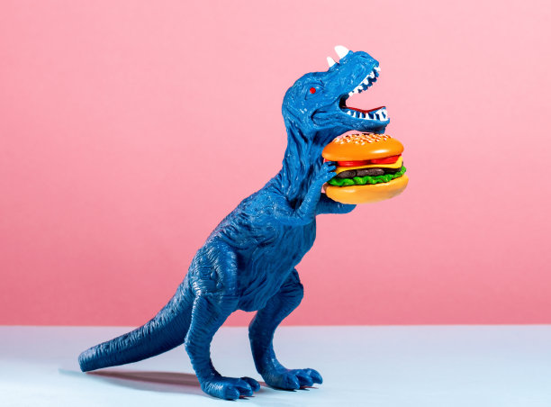 近距离蓝色恐龙拿着汉堡在粉红色和蓝色的背景。图片下载
