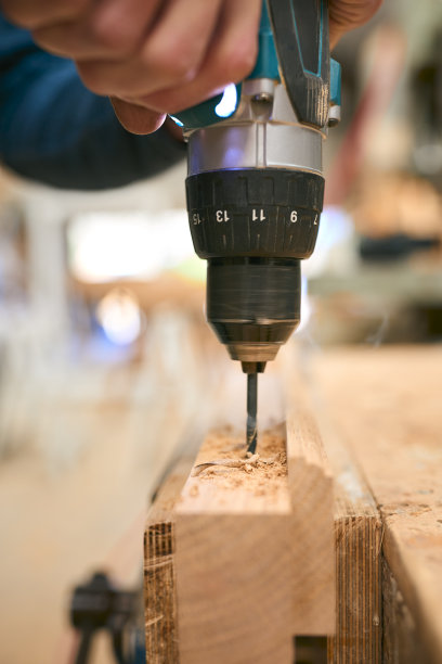 木工在车间工作台上使用无绳电钻的特写图片下载