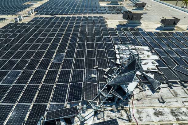 被飓风伊恩摧毁的俯视图安装在工业建筑屋顶上的光伏太阳能电池板产生绿色生态电力。佛罗里达自然灾害的后果图片下载