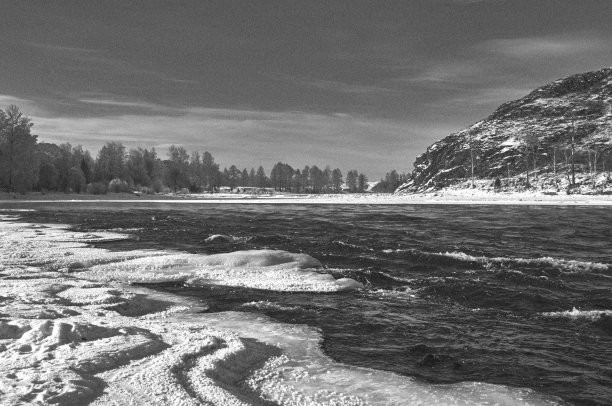 在多云的天空下，冰冻的河岸和远处的山图片下载