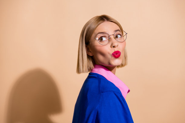 侧面照片美丽的金发鲍勃头发女士在蓝色套头衫噘嘴看空空间风骚孤立米色背景图片下载