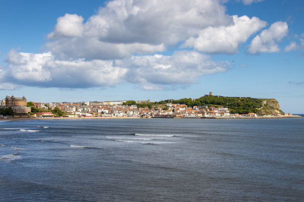 这是英国东约克郡斯卡伯勒镇中心的风景照片，在一个阳光明媚的夏日里，海滩、港口、船只和斯卡伯勒城堡一览无遗图片下载