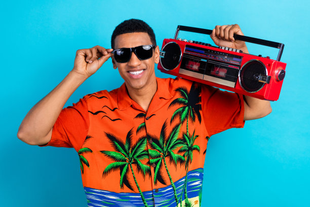 照片心情好酷的家伙穿着印花衬衫听音箱孤立的蓝色背景图片下载