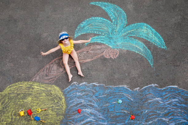 快乐的学龄前小女孩穿着泳装在充气环上，上面有大海、沙子、用彩色粉笔在沥青上画的手掌。可爱的孩子玩粉笔画。夏天，假期，夏天图片下载