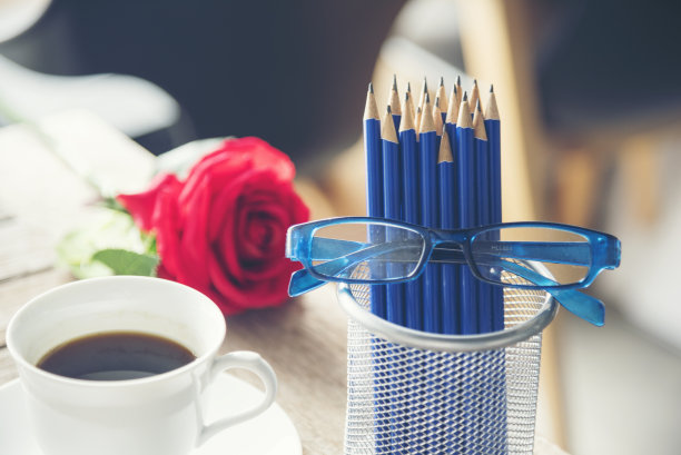 锐利HB蓝色铅笔银花瓶办公用品装饰咖啡杯玫瑰在木桌上。绿色装饰家庭办公桌。木质办公桌磨刀蓝2B铅笔盒家庭办公装饰桌图片下载