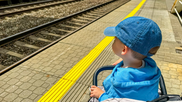 一个小男孩在火车站等火车。图片下载