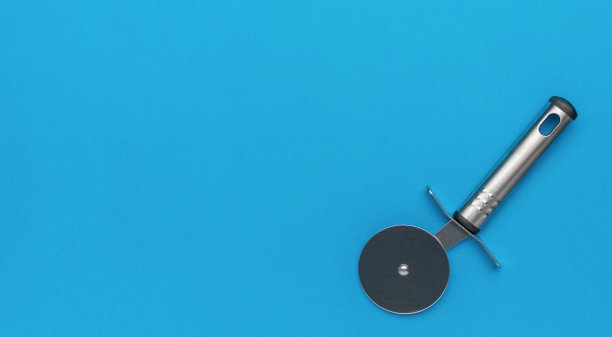 不锈钢披萨刀在蓝色背景-极简厨房用具照片图片下载