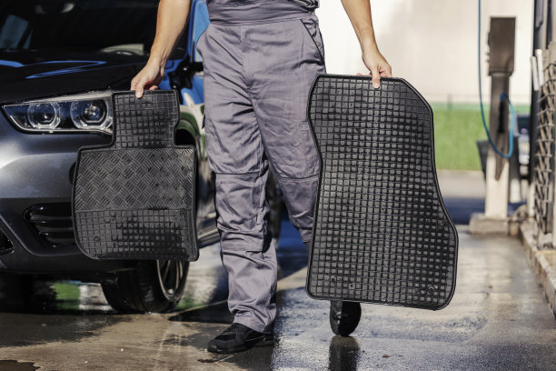 剪短的洗车工在洗车站拿着汽车垫的照片。图片下载