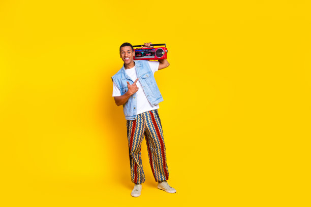 乐观的好男人穿着牛仔裤马甲的全长照片表明在肩膀上孤立的黄色背景音箱图片下载